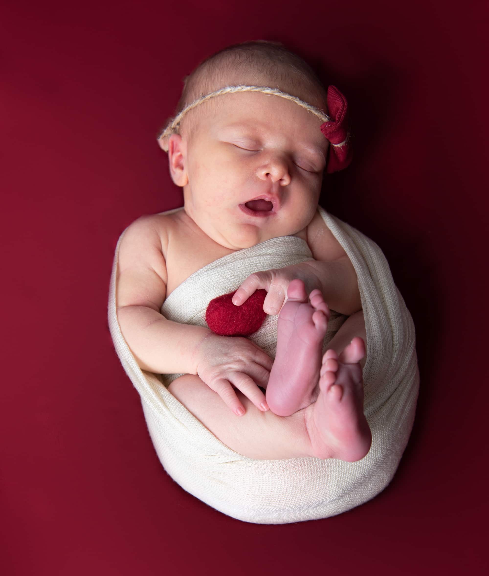 Lily emmitouflée dans un décor rouge lors de sa séance photo de naissance à Meaux - Photos de naissance à Meaux pour Lily