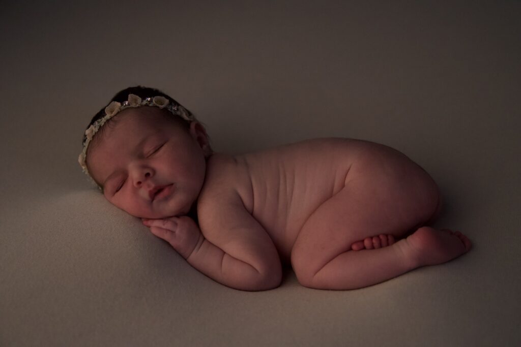 Séance photo naissance de Gabriela au home studio à Meaux, posée paisiblement avec un bandeau floral délicat.