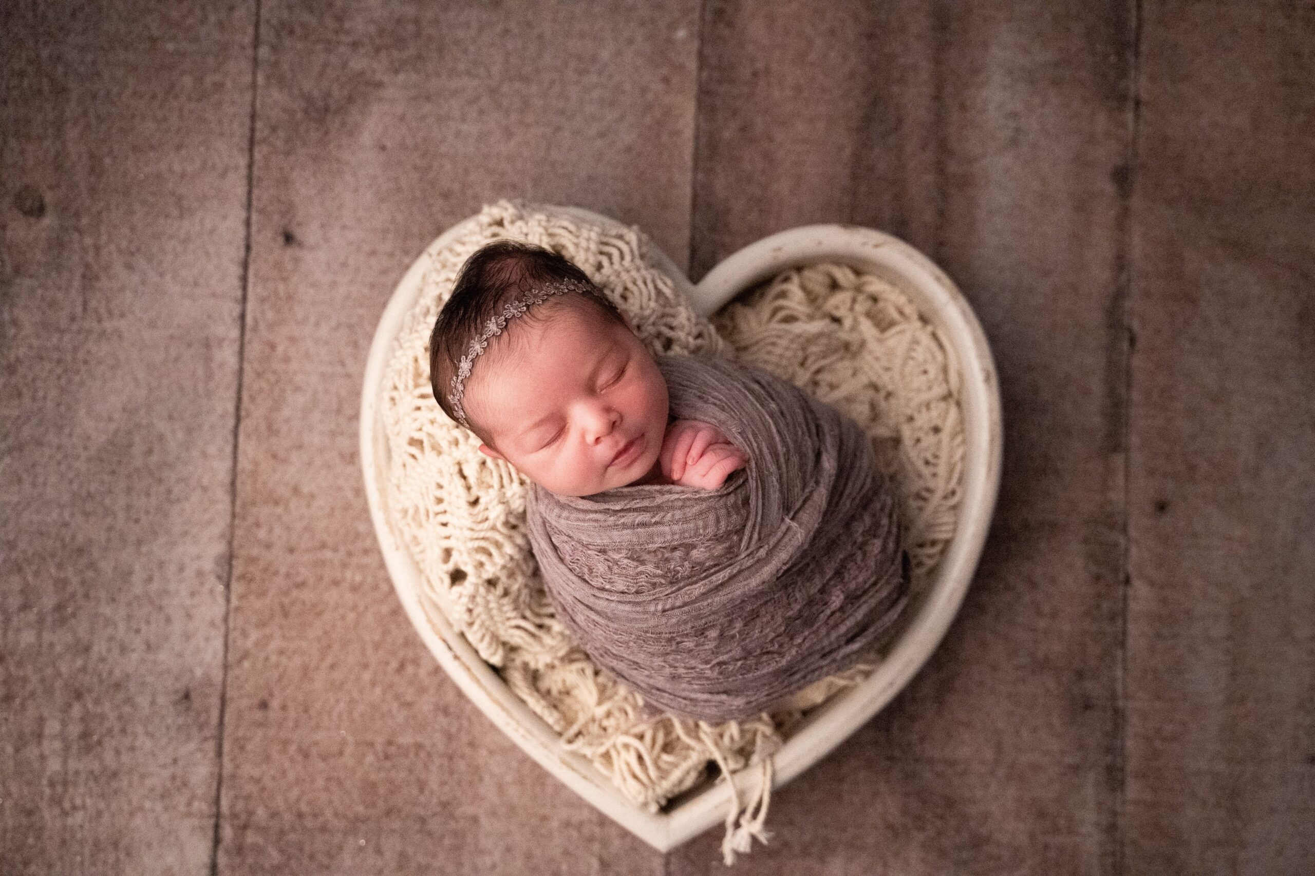 Séance photo naissance de Gabriela au home studio à Meaux, posée dans un panier en forme de cœur avec une couverture douce.